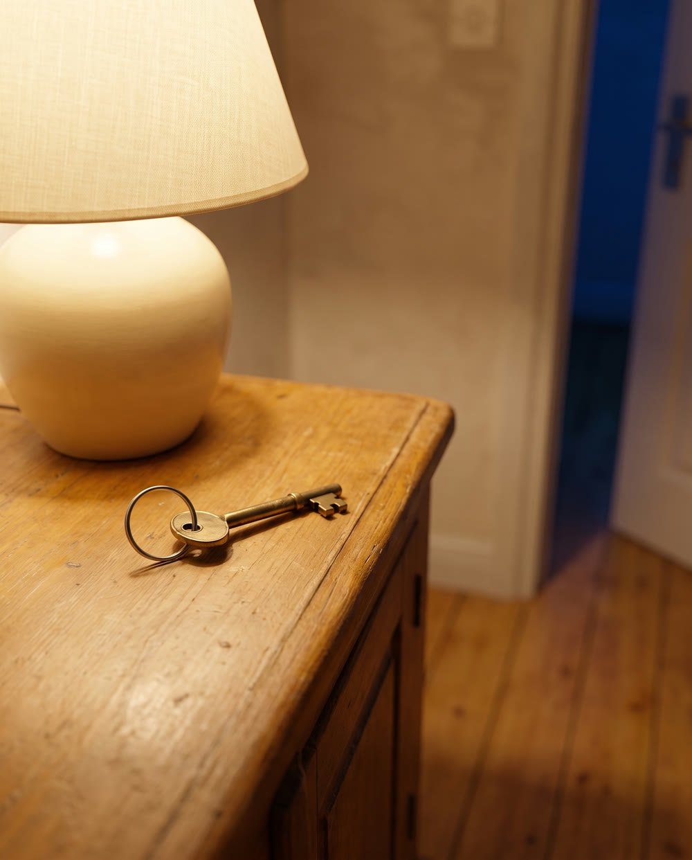 Hausschlüssel auf einer Holzkommode im warm beleuchteten Flur